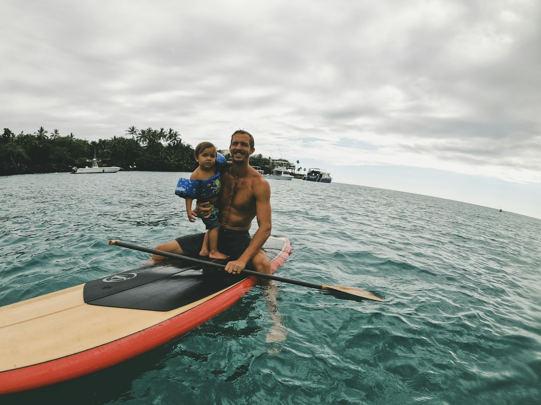 2 men riding on orange kayak on sea during daytime